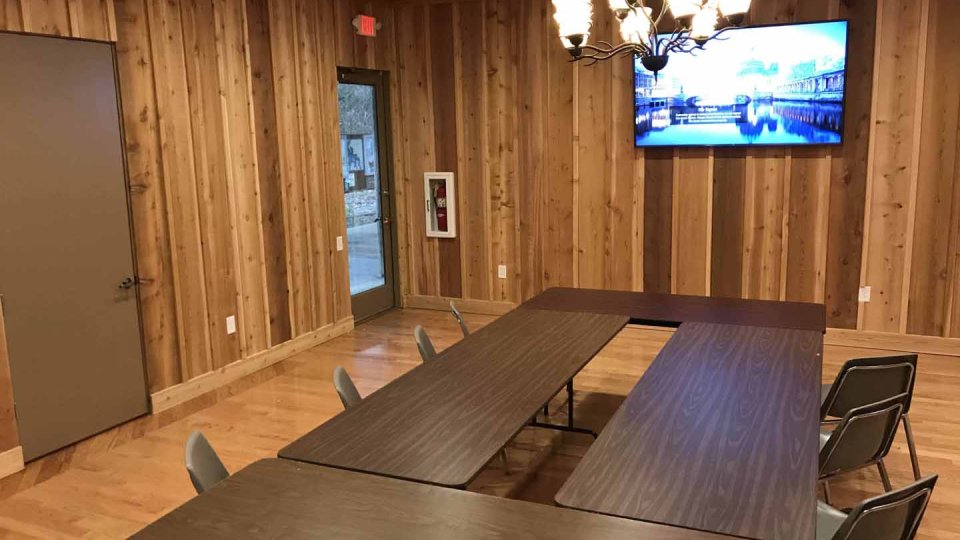 Conference room with wooden walls, U-shaped table, chairs, and a ceiling light.