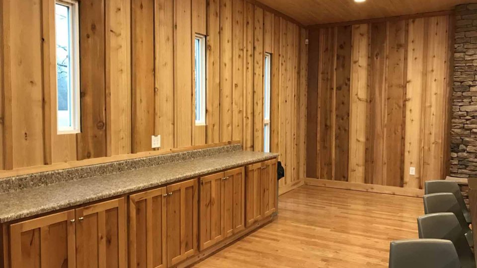 Wood-paneled room with wooden cabinets and small windows.