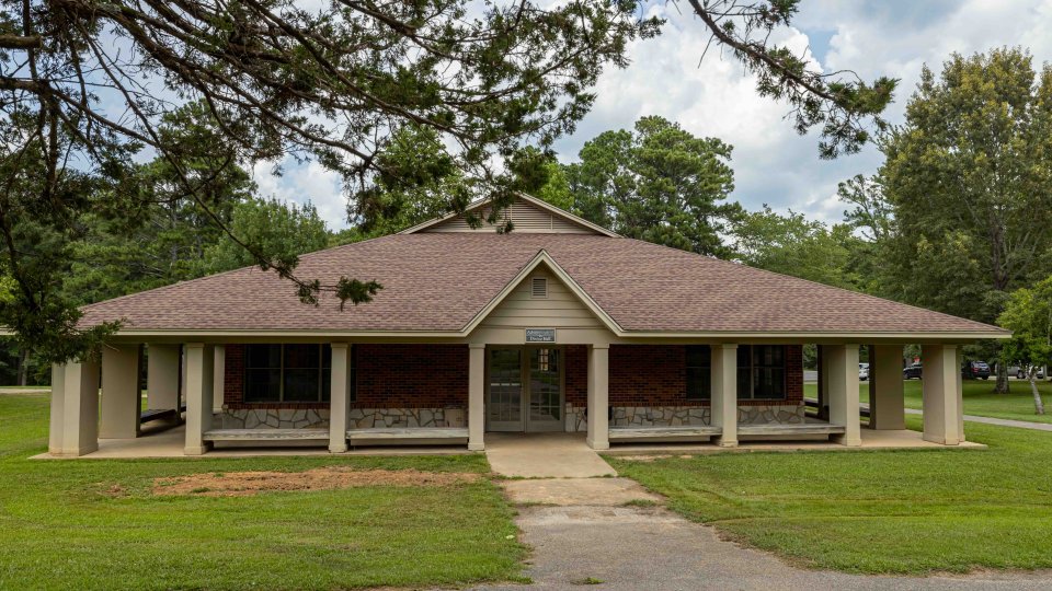 Single-story community center with a brown roof and wrap-around porch.