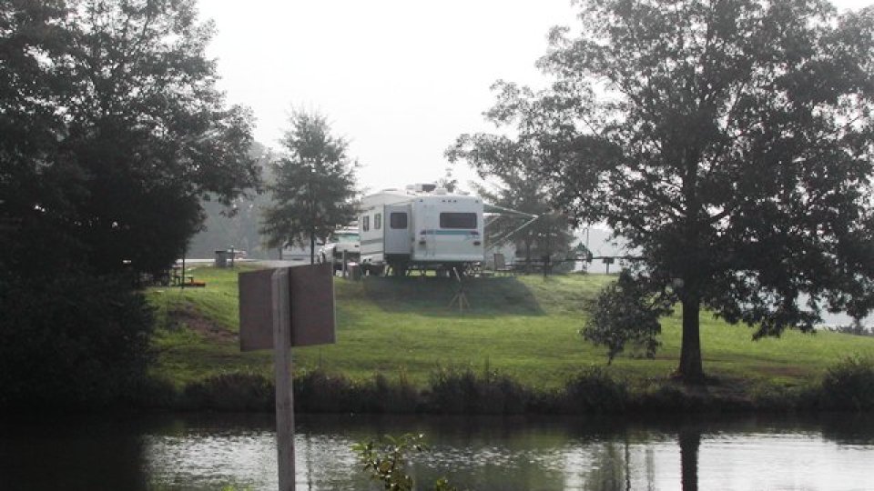 RV parked near trees by a serene lake.