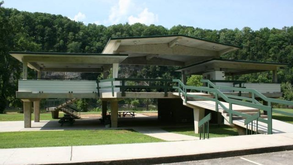 Modern pavilion with ramps and stairs in a park setting.
