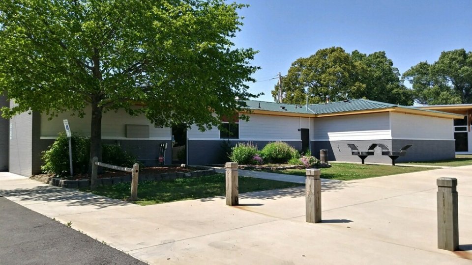 School building with trees and walkway, under a clear blue sky.