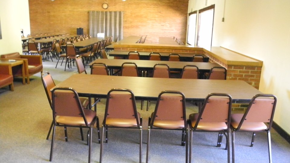 Rectangular tables with chairs in a large meeting room.