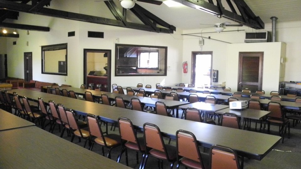 Spacious hall with long tables and brown chairs.