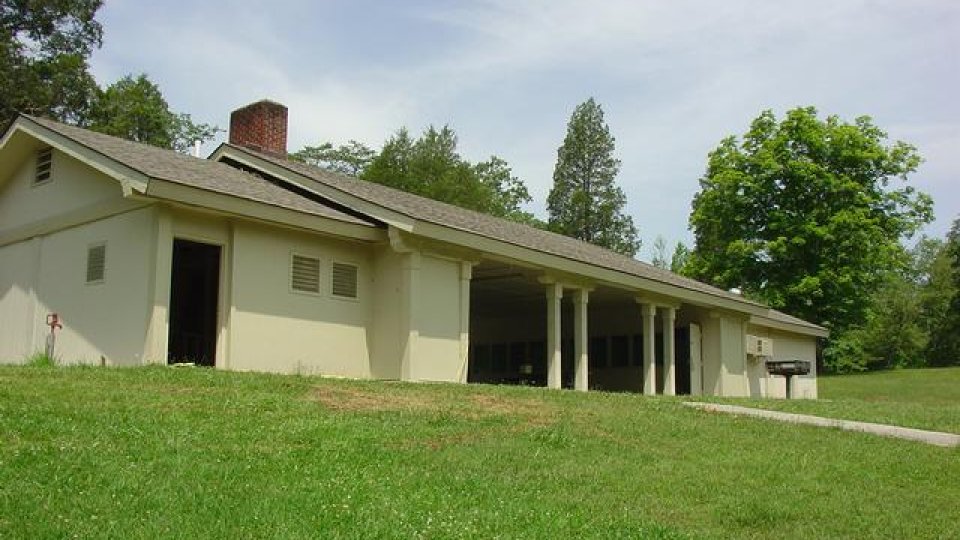 Single-story beige building with a long porch set against green lawns and trees.