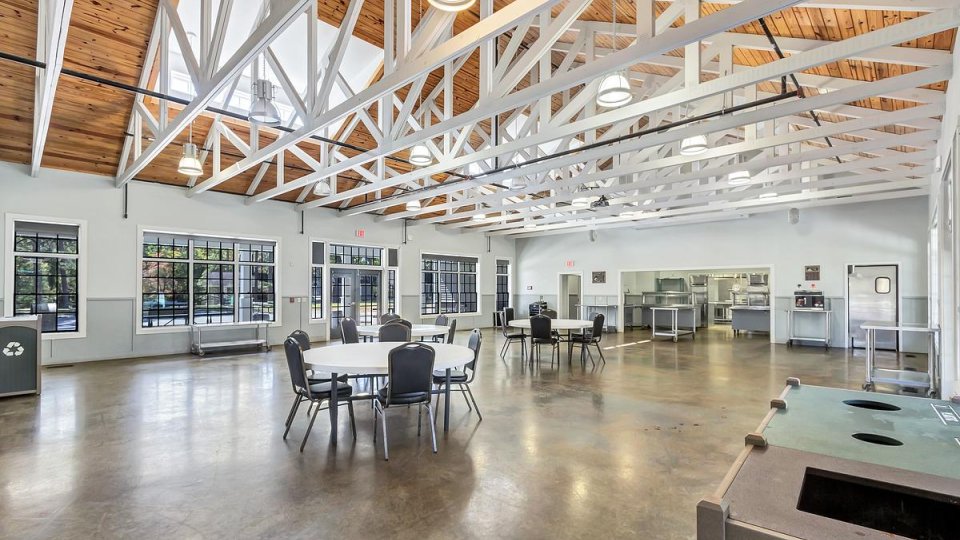 Spacious cafeteria with wooden ceiling beams and multiple seating areas.