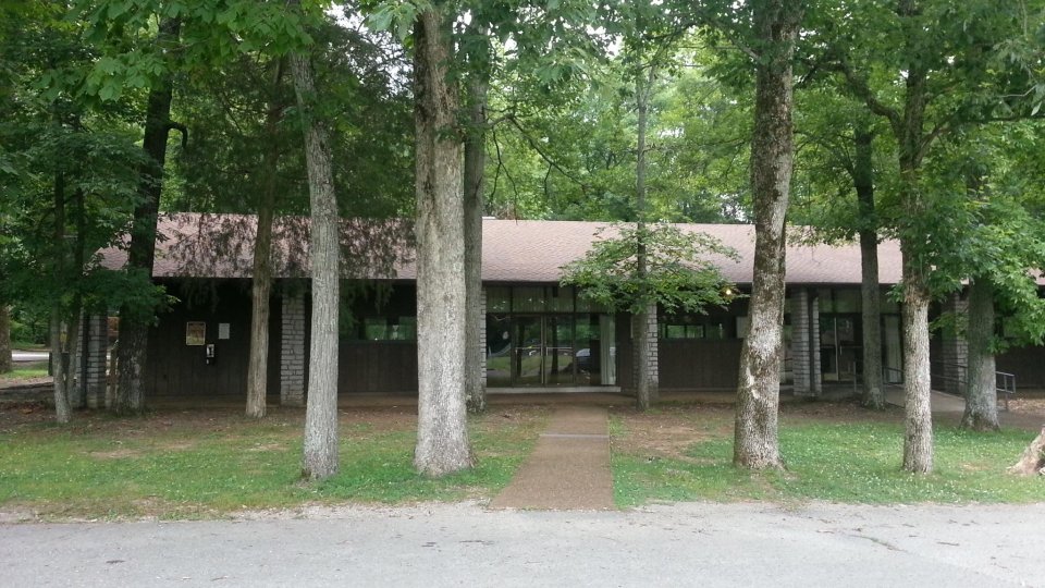 Brown building with a sloped roof surrounded by trees.