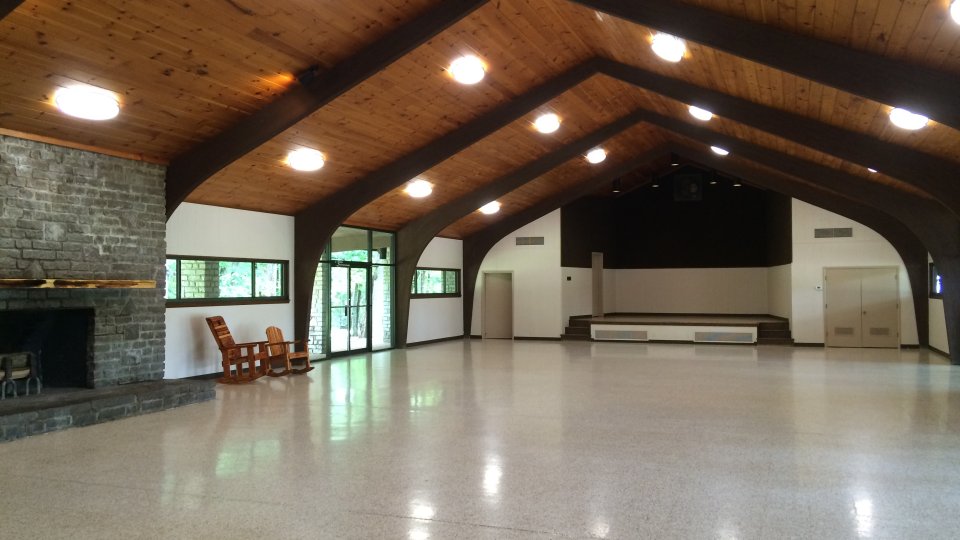 Spacious hall with wooden ceiling and stone fireplace.