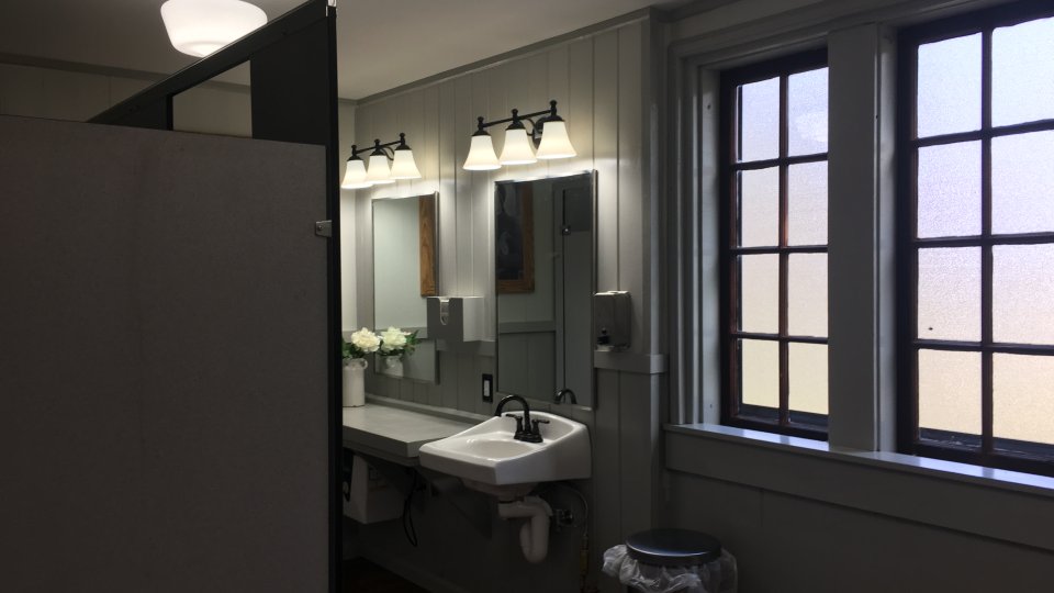 Restroom with sink, mirror, lights, and two windows.