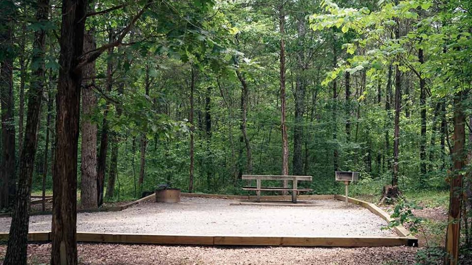 Outdoor wooden sandpit and picnic table in a forest.