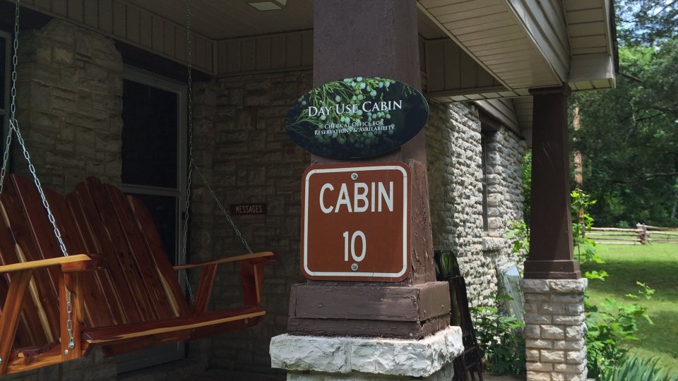 Cabin porch with a swing and signpost.