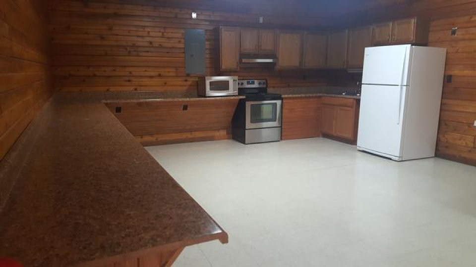 Wood-paneled kitchen with white appliances and granite countertop.