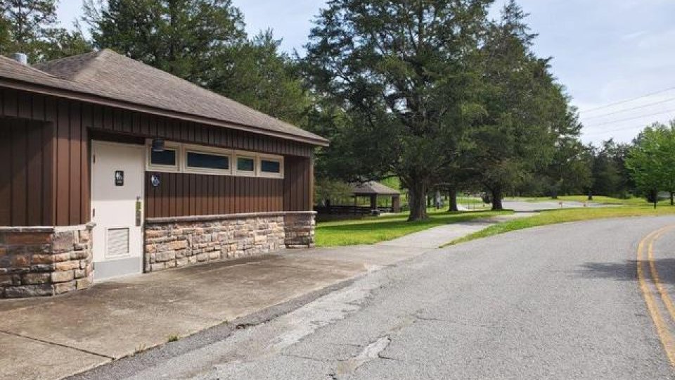 Brown building with stone accents beside an empty road and green trees.