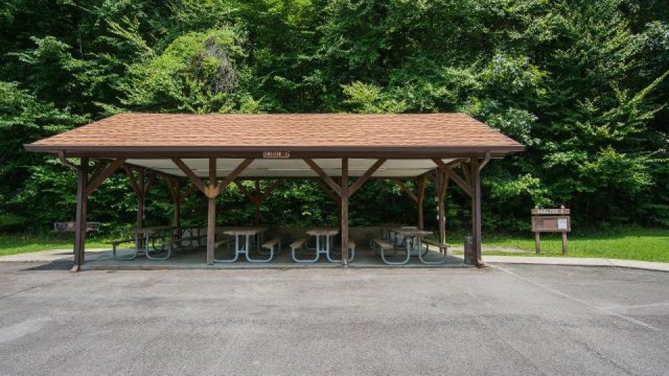 Shelter with picnic tables in a wooded area.