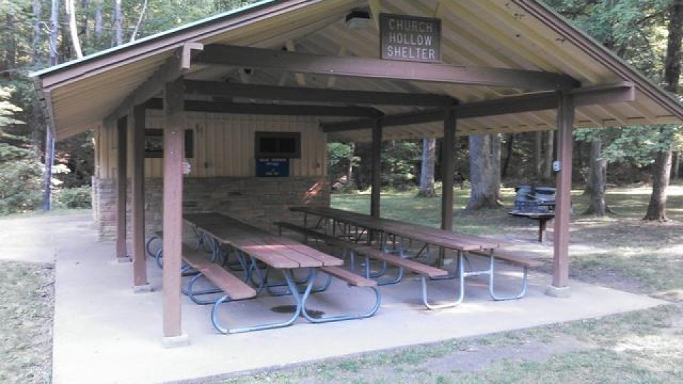 Shelter with picnic tables in a wooded area.