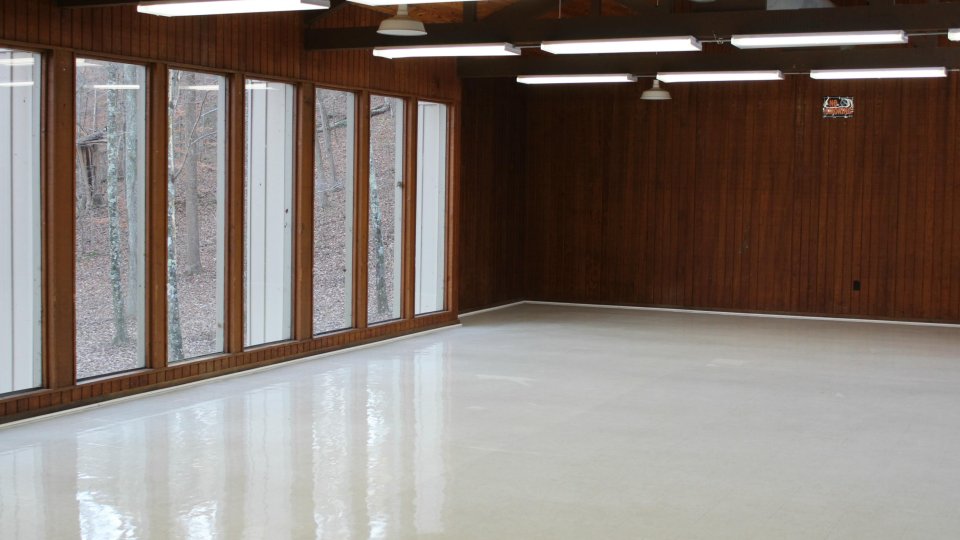 Spacious empty room with large windows and wood-paneled walls.