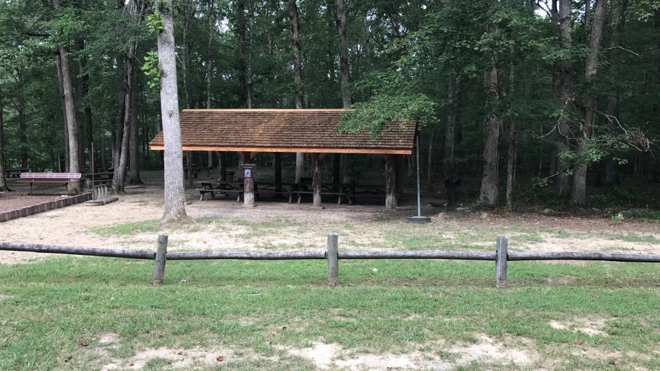 Pavilion in a park surrounded by trees and grass.