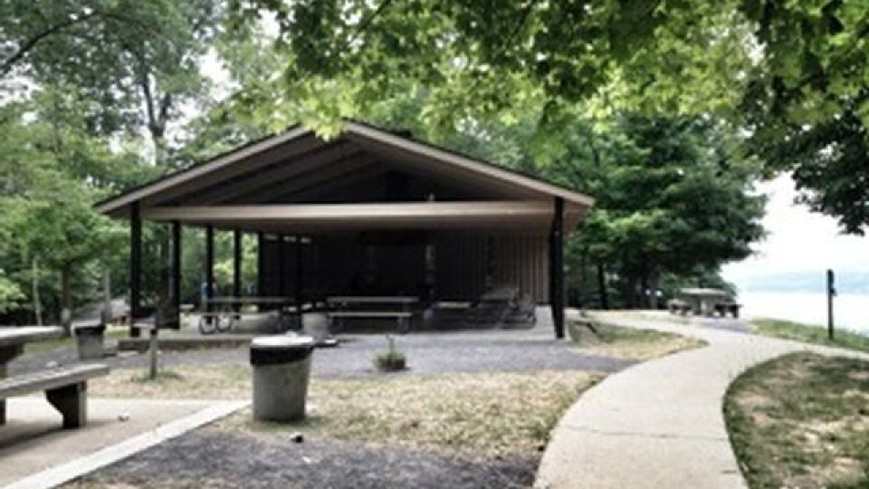 A park pavilion with picnic tables and a winding path surrounded by trees.