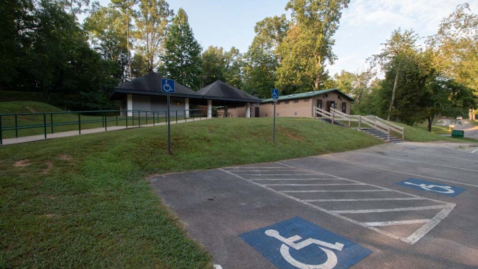 Accessible parking spots in front of a park facility with trees and blue sky.