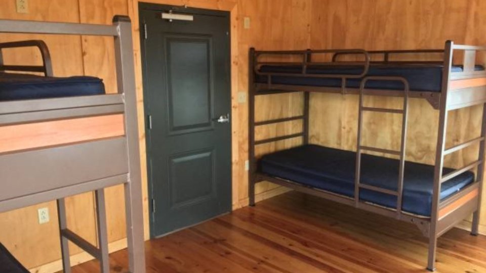 Bunk beds in a wooden-floored room with a dark door.