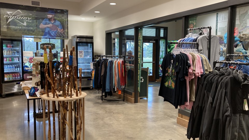 Store interior with clothing racks, walking sticks, and a beverage cooler.