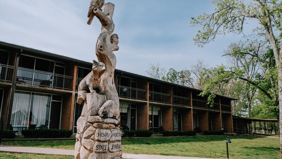 Wooden statue of animals at Henry Horton State Park, in front of brick buildings.