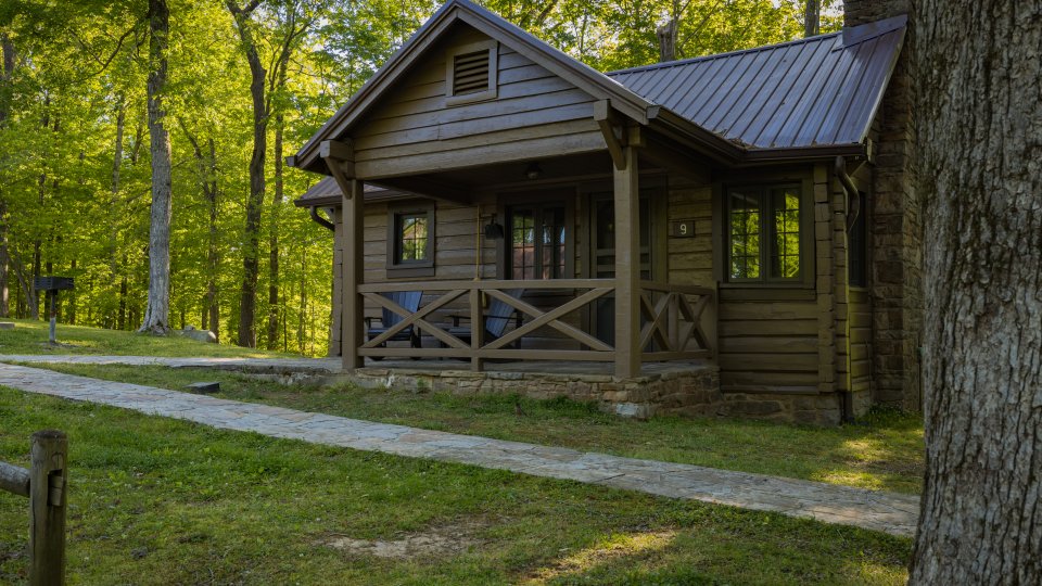 A four‑image collage showing a rustic log cabin exterior, misty meadow landscape, and two cozy interior scenes with wooden furnishings.