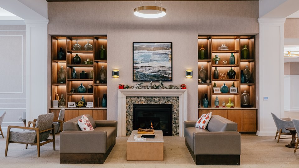 Elegant living room with sofas, a fireplace, and decorative shelves.