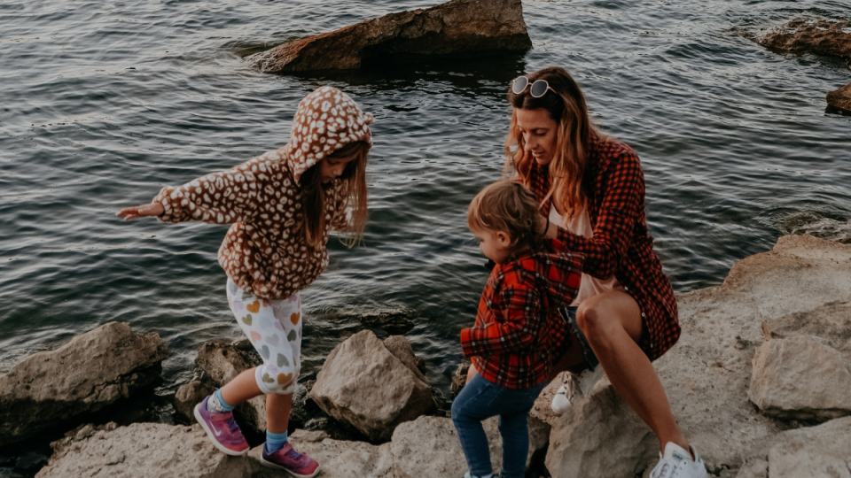 A family sits on rocks next to a lake during the fall.