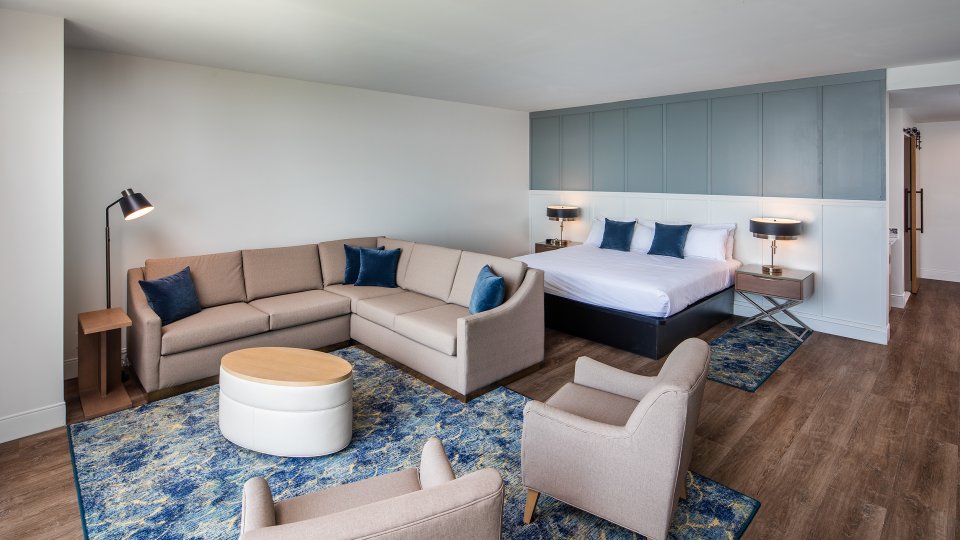 Spacious hotel room with a seating area, large bed, and modern decor.
