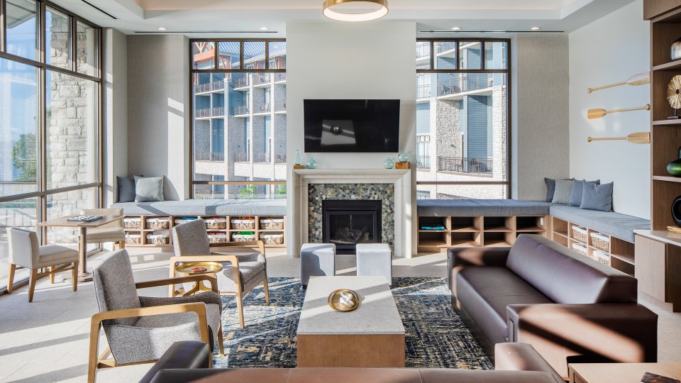 Modern lounge with sofas, armchairs, large windows, and a fireplace.