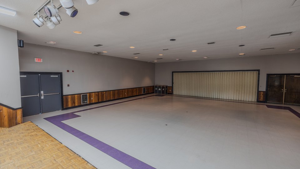 Spacious multipurpose room with folding partition and stage lighting.