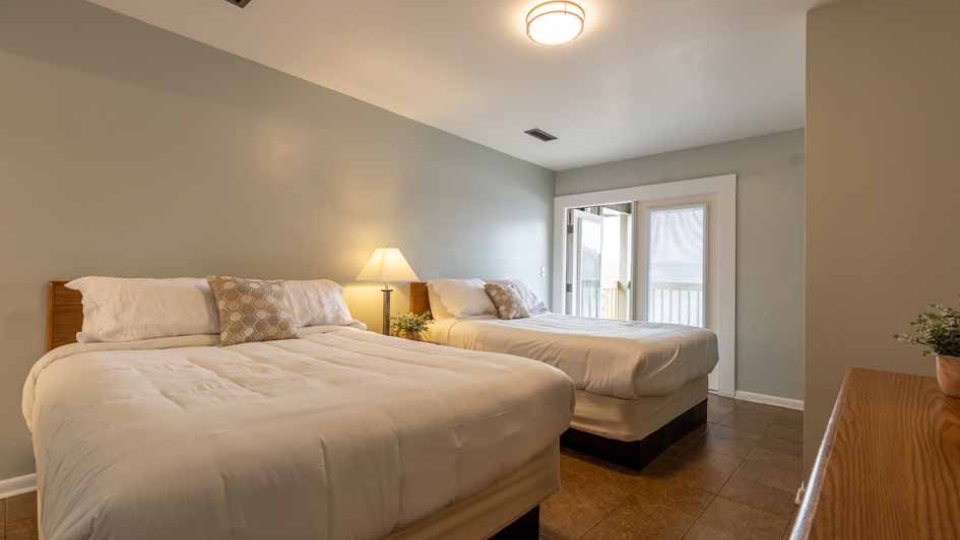Bedroom with two double beds, a nightstand, and a door leading to a balcony.