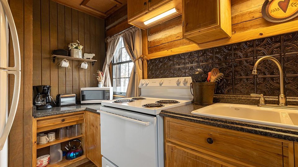 A galley kitchen with a window, stove, and sink in view.