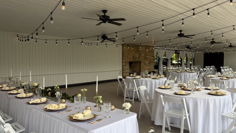 Elegant indoor wedding reception setup with white draped tables and string lights.