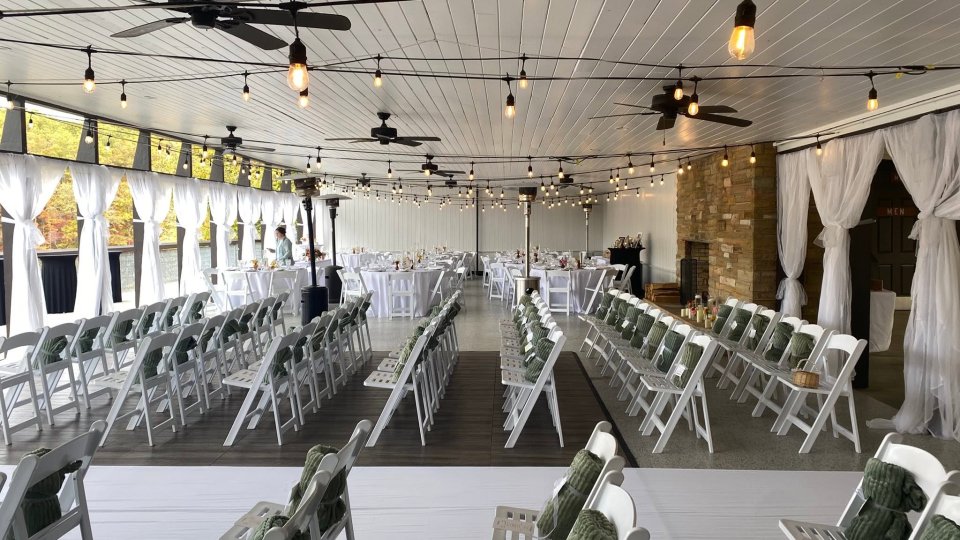 Elegant outdoor wedding venue with rows of white chairs and string lights.