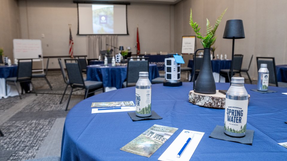Conference room setup with tables, chairs, and presentation screen.