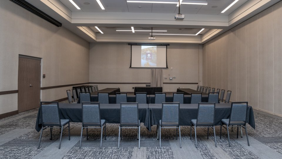 Conference room with U-shaped table setup and a projector screen.