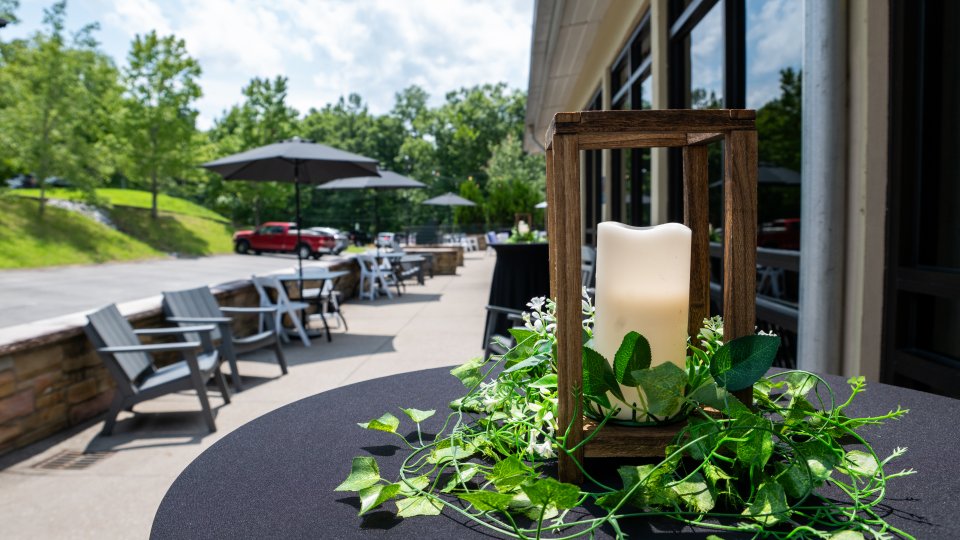 Candle centerpiece with greenery at an outdoor café terrace.