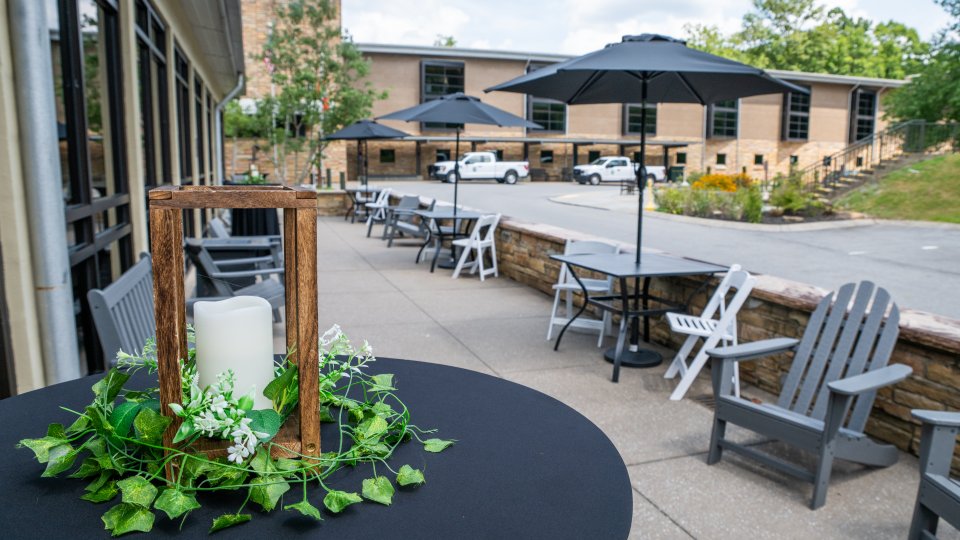 Outdoor cafe with umbrellas and candle centerpiece on a table.