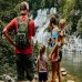 Family observing a waterfall in a lush, wooded area.