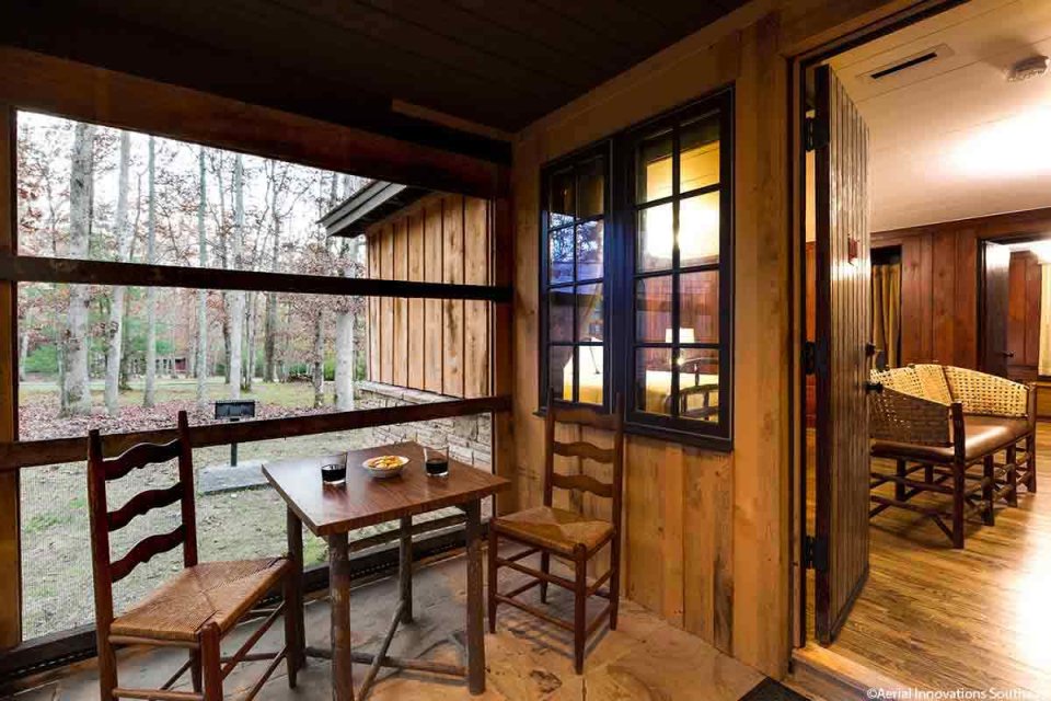 Wooden screen in patio with wooden chairs, table, and window