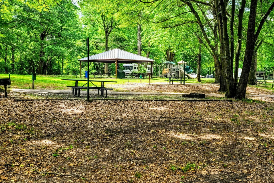 Park with picnic tables, gazebo, and lush green trees.