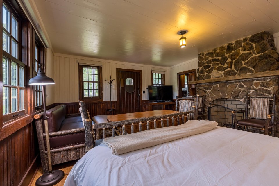 Cozy rustic bedroom with a stone fireplace and wooden furniture.