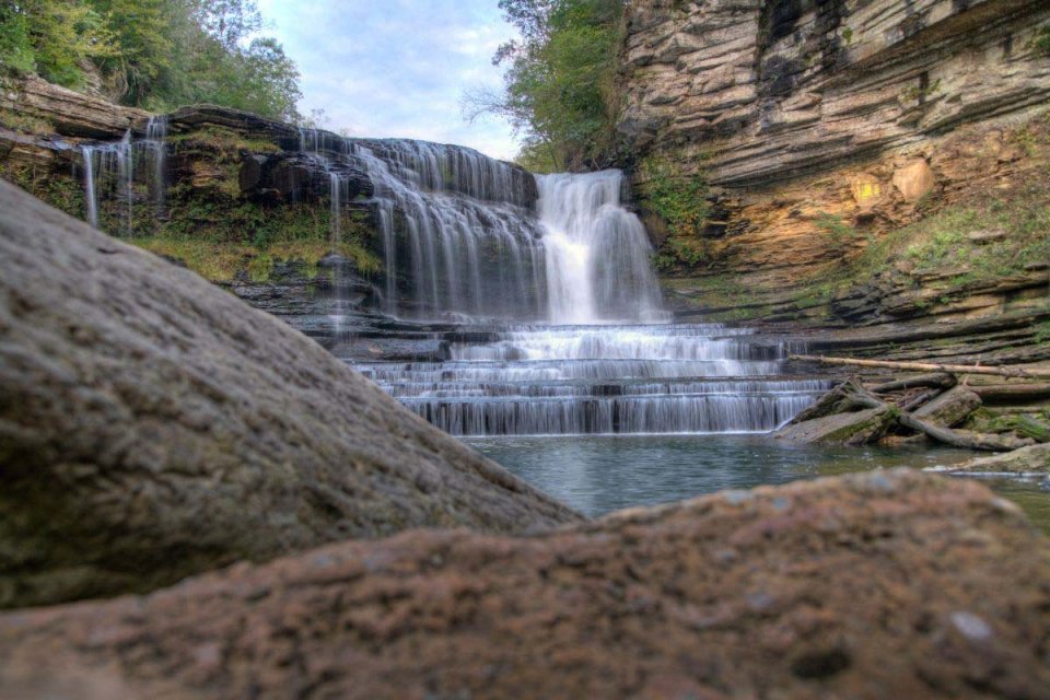 Water cascades over a rocky ledge into a serene pool below.