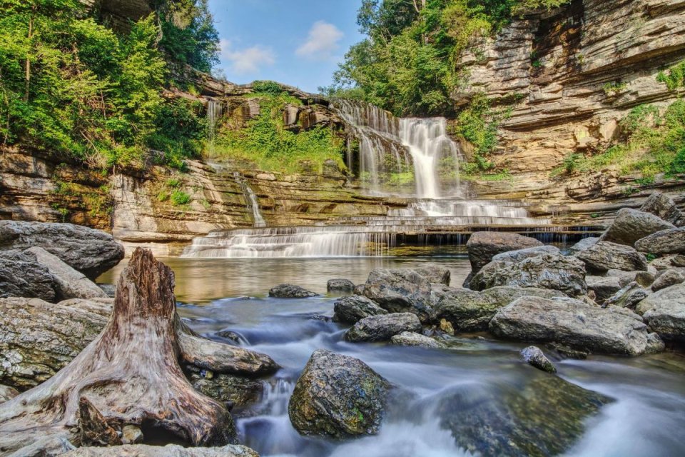 Scenic waterfall cascading into a rocky pool surrounded by lush greenery.