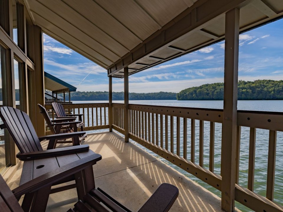 Wooden chairs on a porch overlooking a tranquil lake.