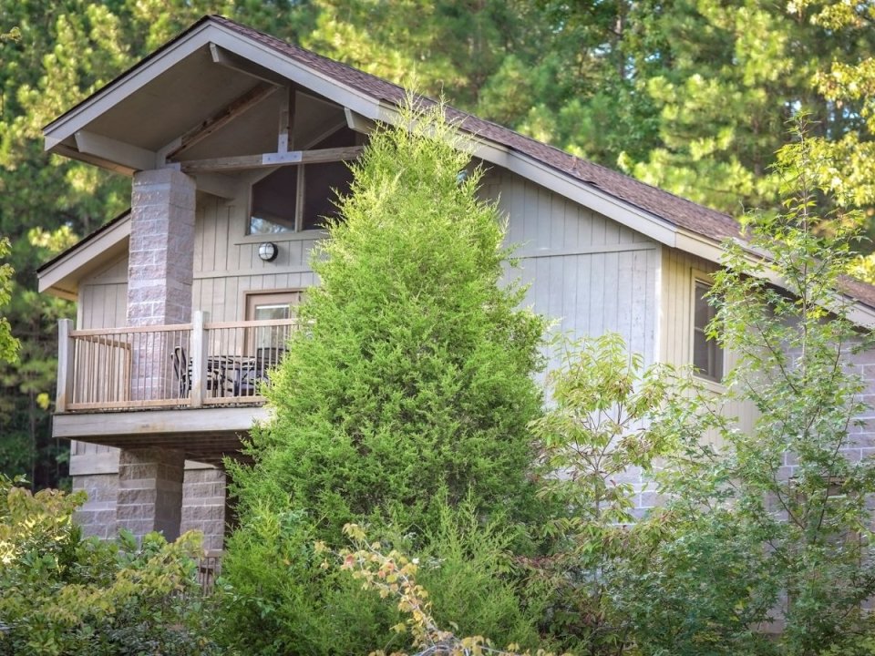 Wooden house with a balcony surrounded by trees.