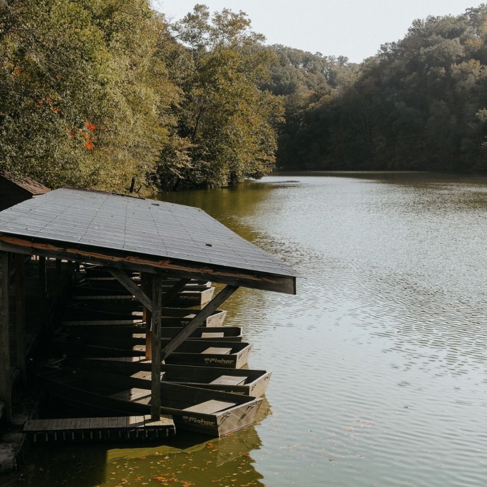 Wooden boathouse on a tranquil lake surrounded by forest.
