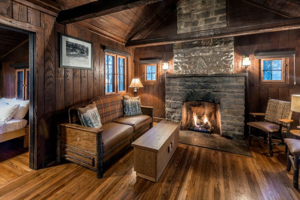 Cozy cabin living room with a lit fireplace and wooden furniture.